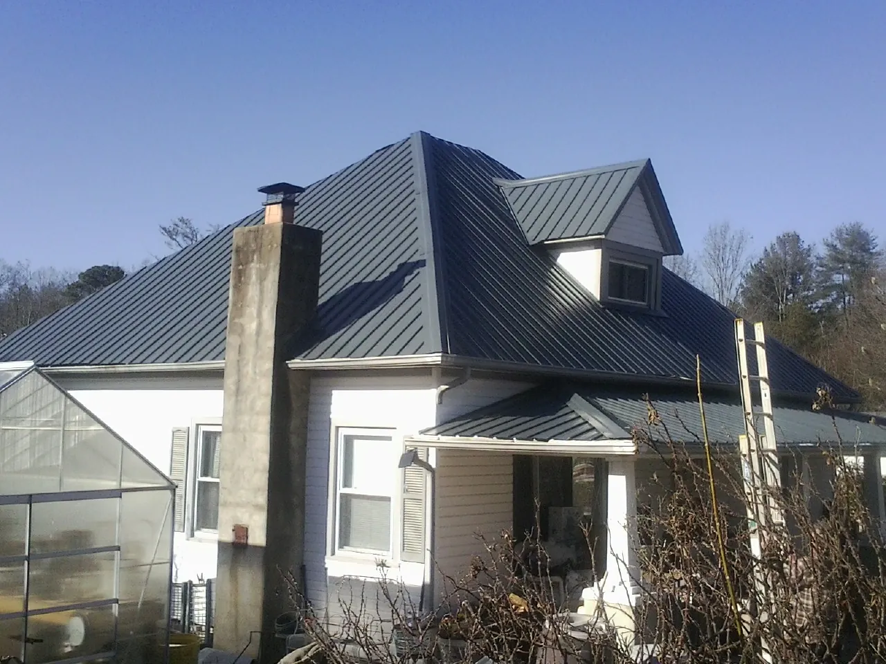 Dark blue standing seam metal roof on a white farmhouse with dormer — Slate & Tile Roof Repair by Roofing Brothers in Eastham