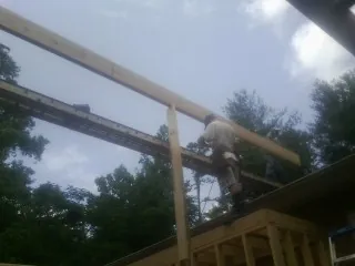Carpenter setting a ridge beam over a new addition frame — Ice Dam Removal by Roofing Brothers in Eastham