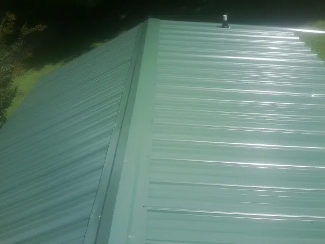 New green metal panels meeting at the ridge of a roof — Flat Roof Repair work by our crew in Eastham