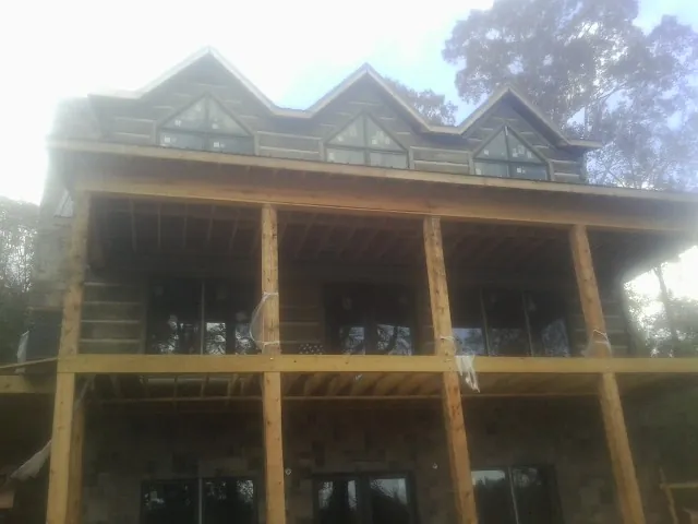 Dormers and porch framing on a large log home under construction — Roof Coating work by our crew in Eastham