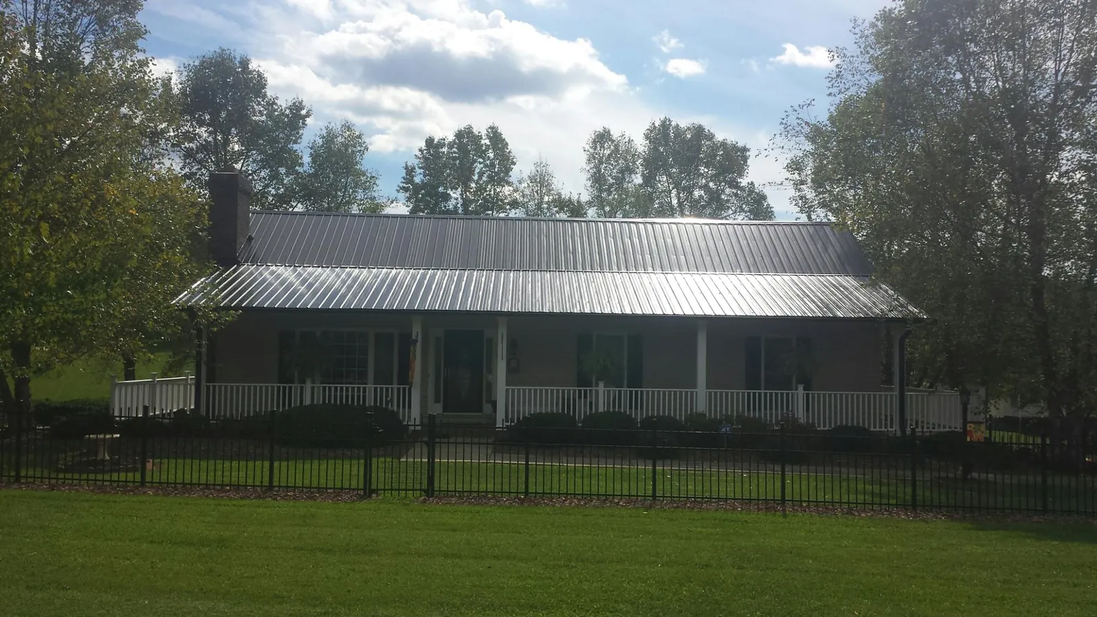 Gray metal roof on a brick ranch with a full width front porch — Gutter Guard Installation work by our crew in Eastham