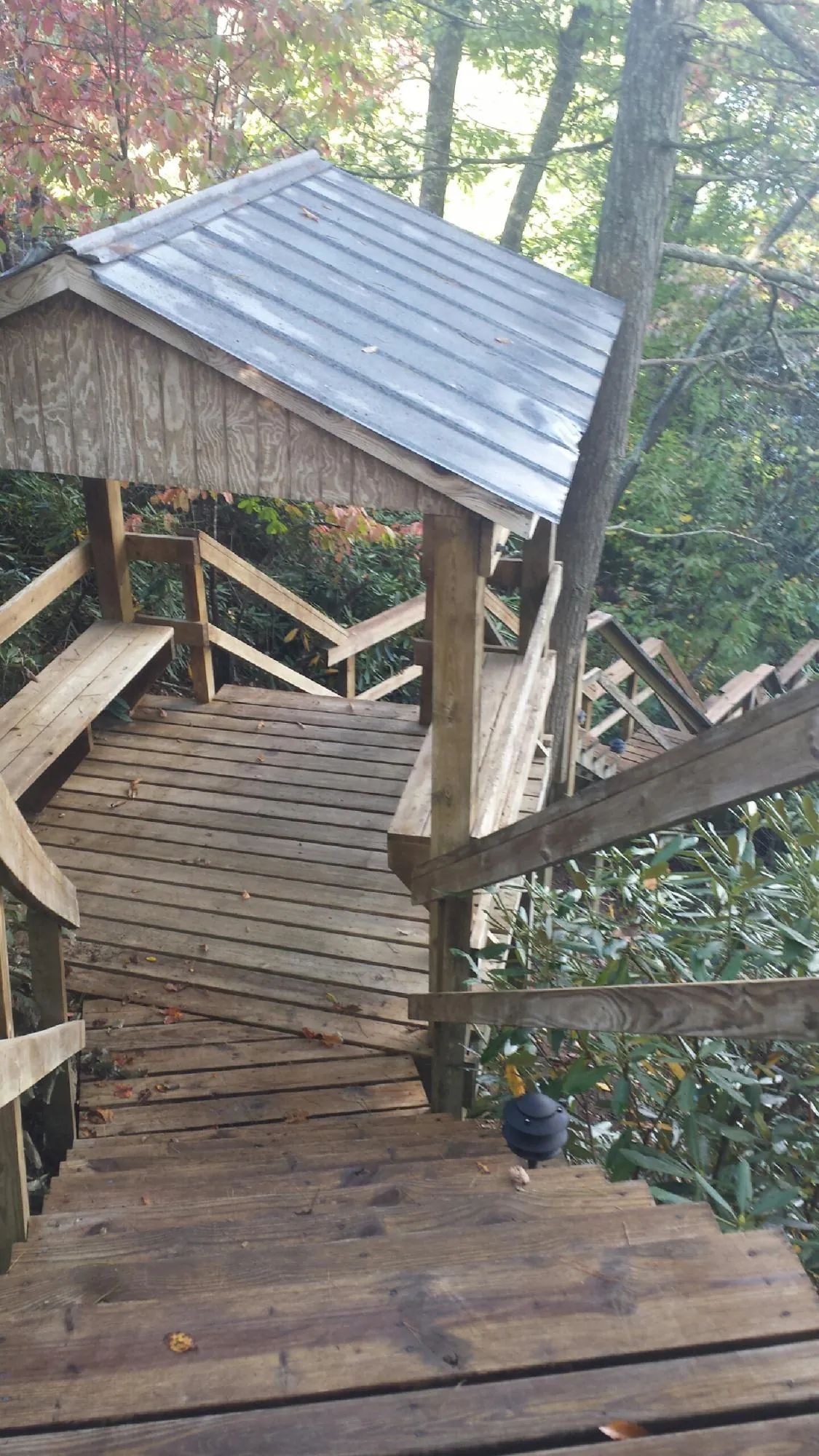 Metal roofed shelter over wooden steps on a wooded walkway — Skylight Repair & Installation work by our crew in Eastham